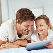 father and daughter smiling and looking at tablet