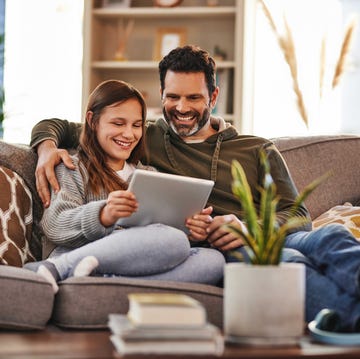 father and daughter looking at an ipad and laughing