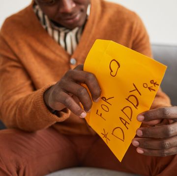 close up of african american man opening letter for daddy as handmade gift for fathers day, copy space