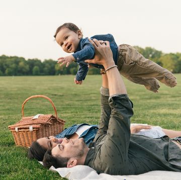 a dad holding up a baby in the air as a mom looks on