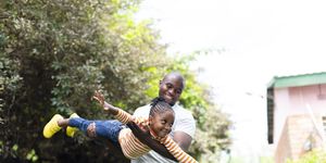 happy little girl flying as father holds her in the air