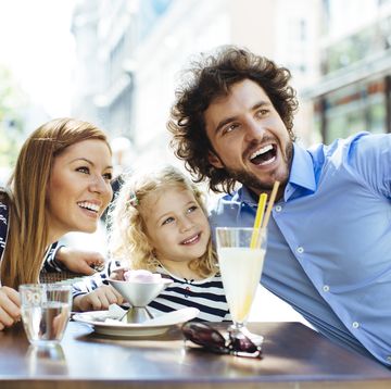 cheerful family with one child sitting in a restaurant refreshing, having fun and making selfie with smart phone