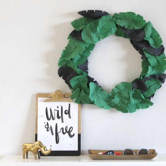 paper green banana leaf summer wreath on a wall above sign that says "wild and free"