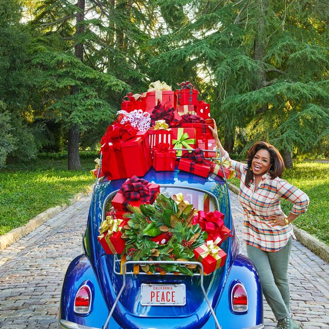 oprah standing next to a vintage blue beetle car loaded with red holiday gifts