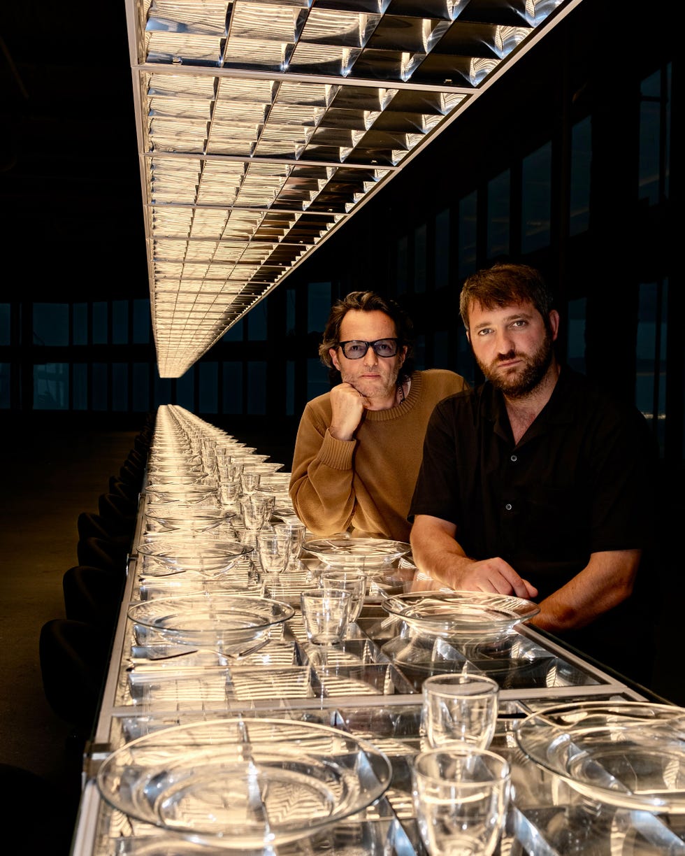 Extended dining table set with transparent plates and glasses.