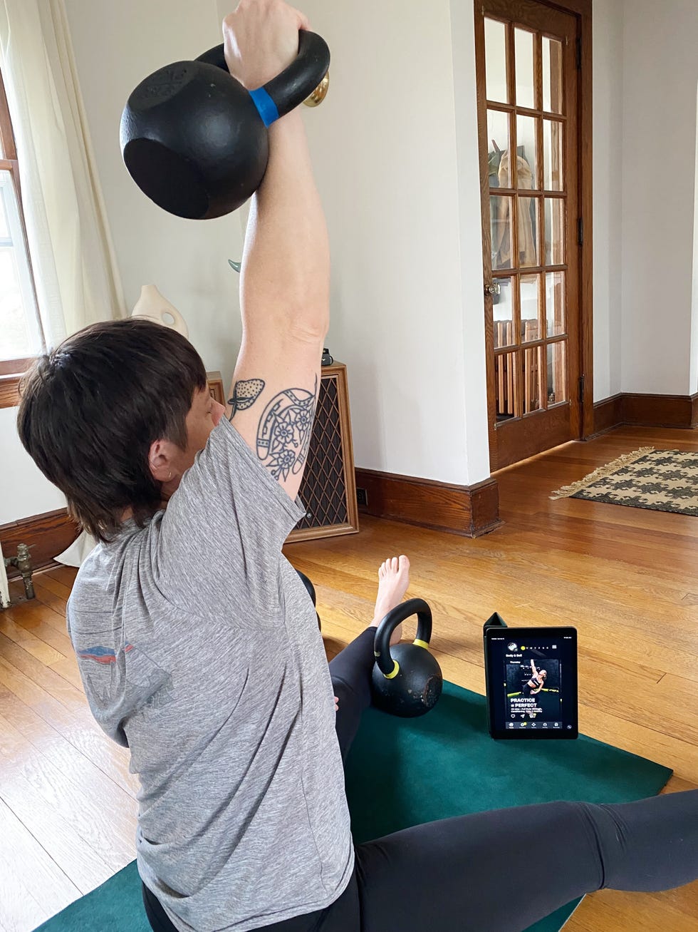 person performing a kettlebell exercise while following an online workout