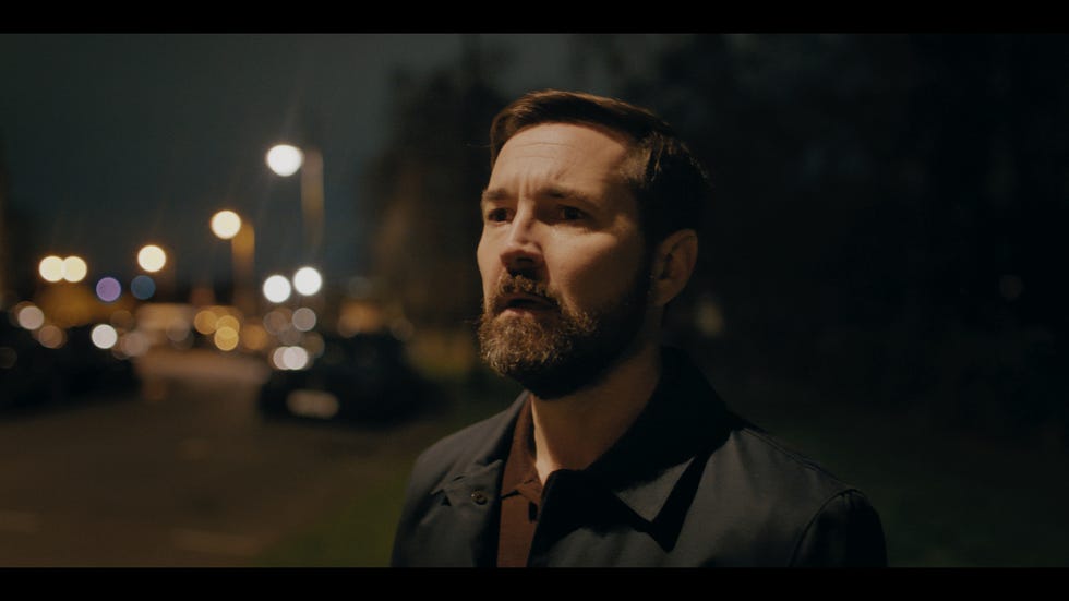 a man standing in a dimly lit urban environment at night