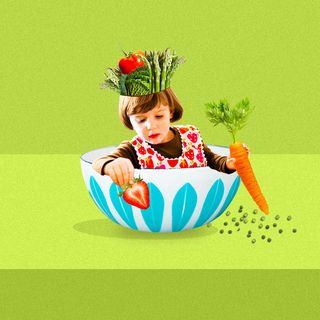little girl sitting in a bowl holding veggies