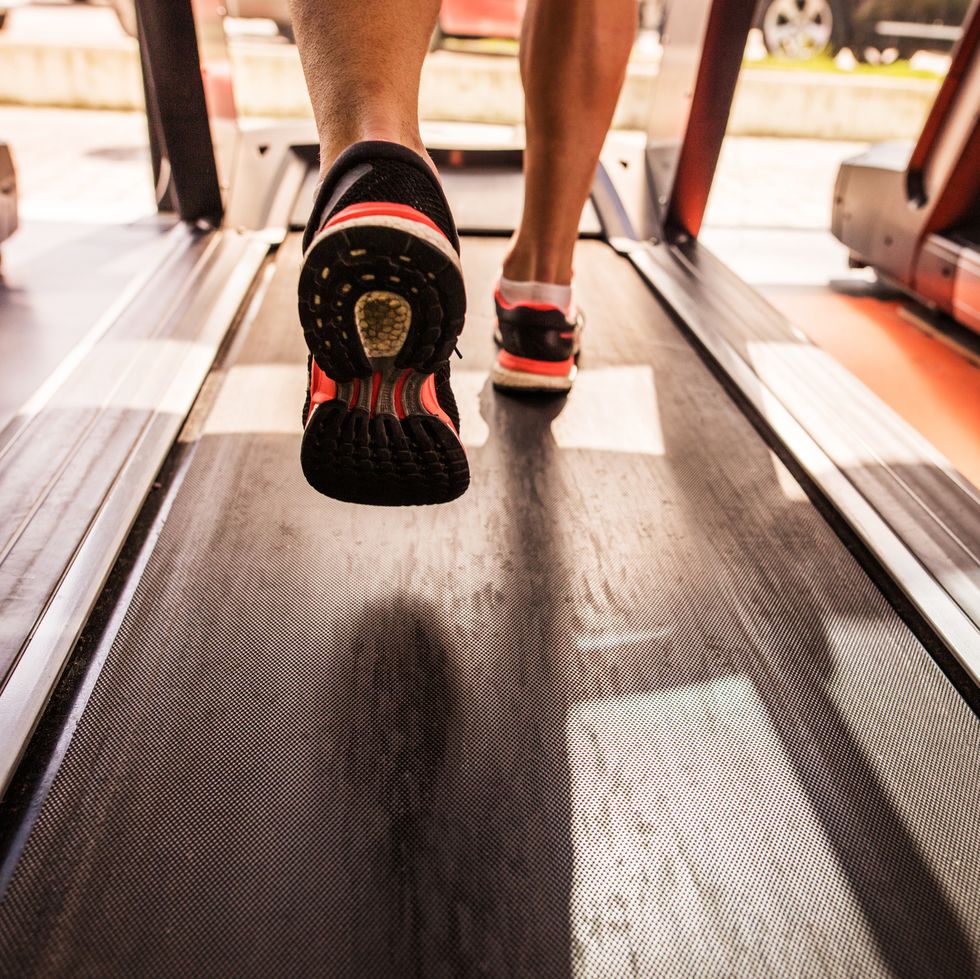 Feet of a runner on treadmill in a gym. Treadmill Workout: HIIT and Running Tips