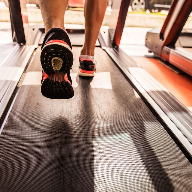 Feet of a runner on treadmill in a gym.