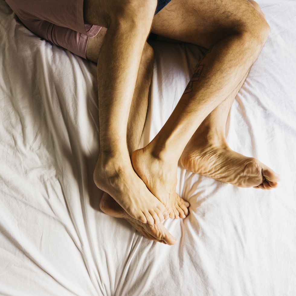 feet of affectionate gay couple bonding in bed