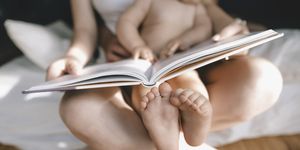 pies de un bebé sentado en el regazo de su madre leyendo un libro