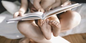 pies de un bebé sentado en el regazo de su madre leyendo un libro