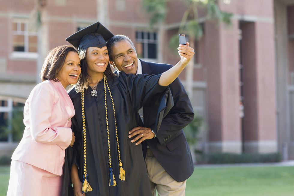 una ragazza fa un selfie con i genitori il giorno della sua laurea