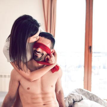 female and blindfolded male in bed with roses
