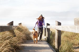 een vrouw loop hard met haar hond in de buurt van het strand