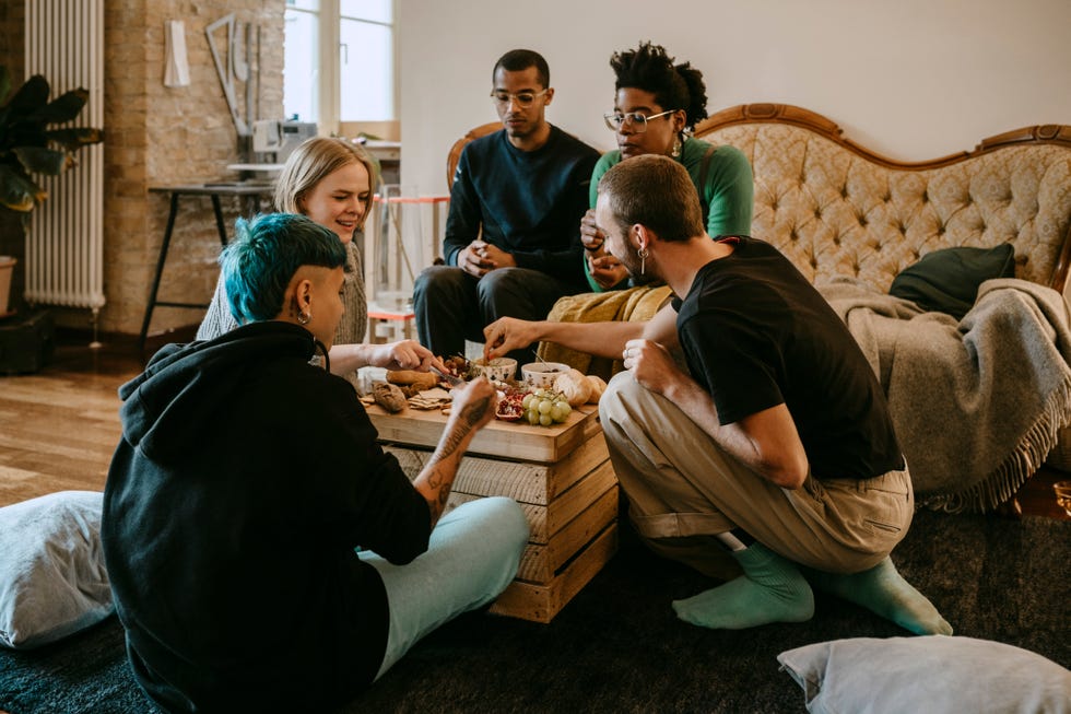 female and male friends having breakfast in living room at home