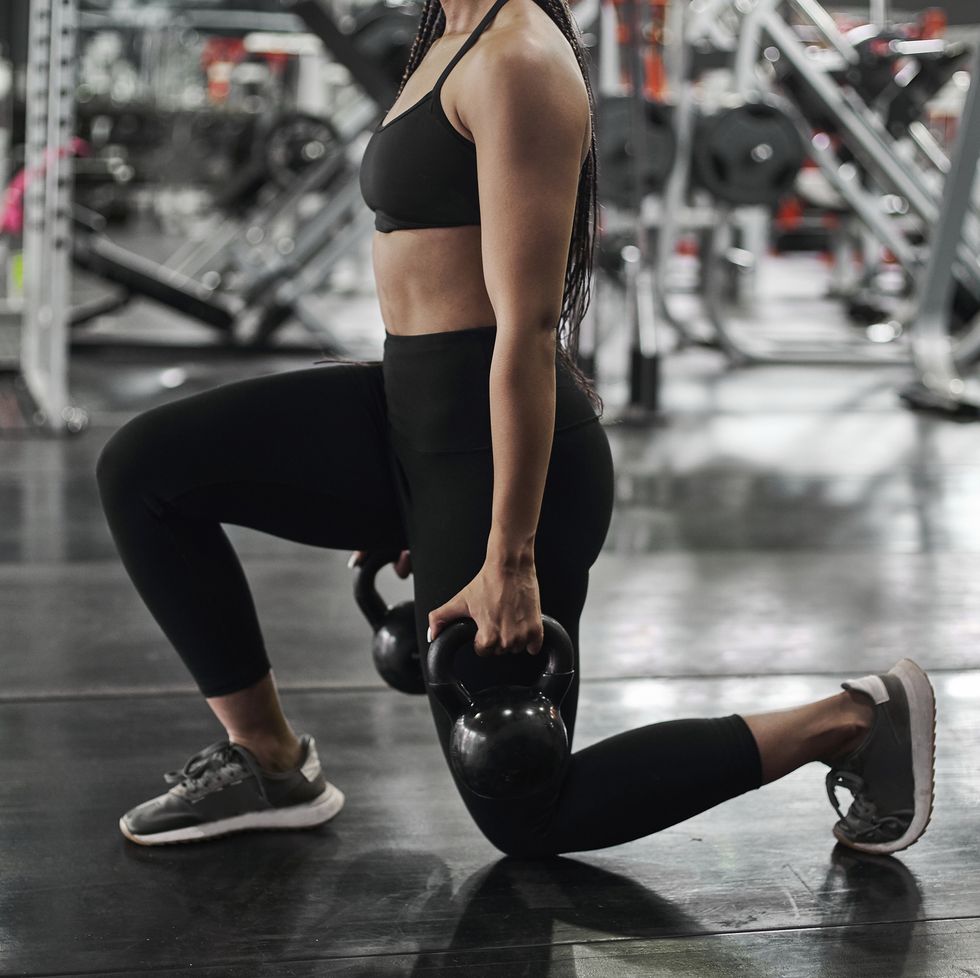 female athlete doing lunges with kettlebells