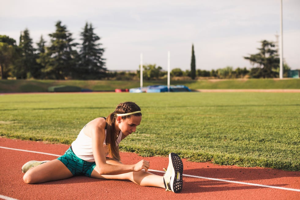 joven estirando en la pista de atletismo