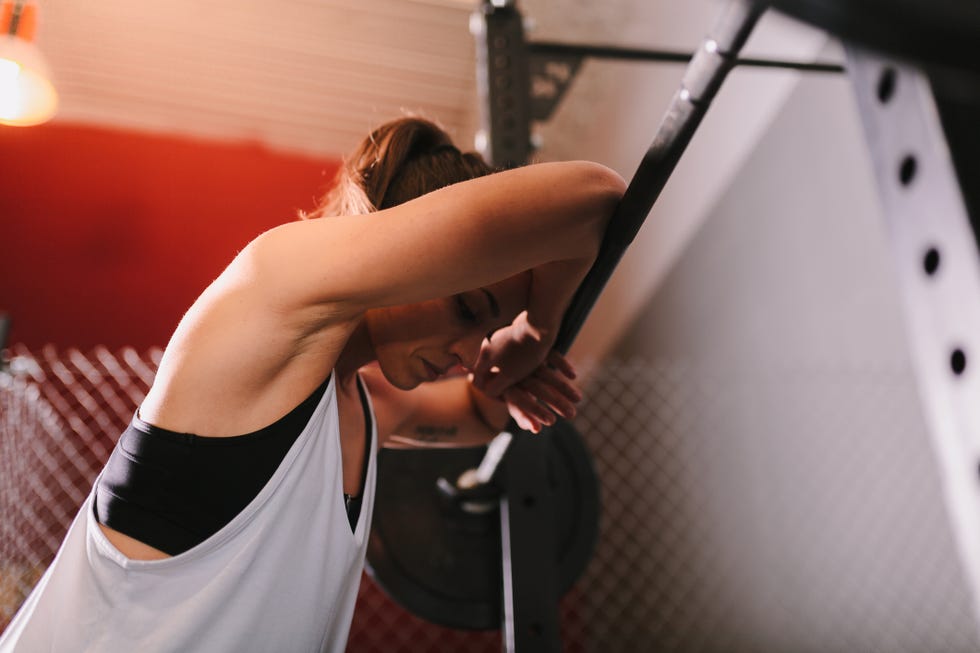 female athlete exercising with barbell in gym