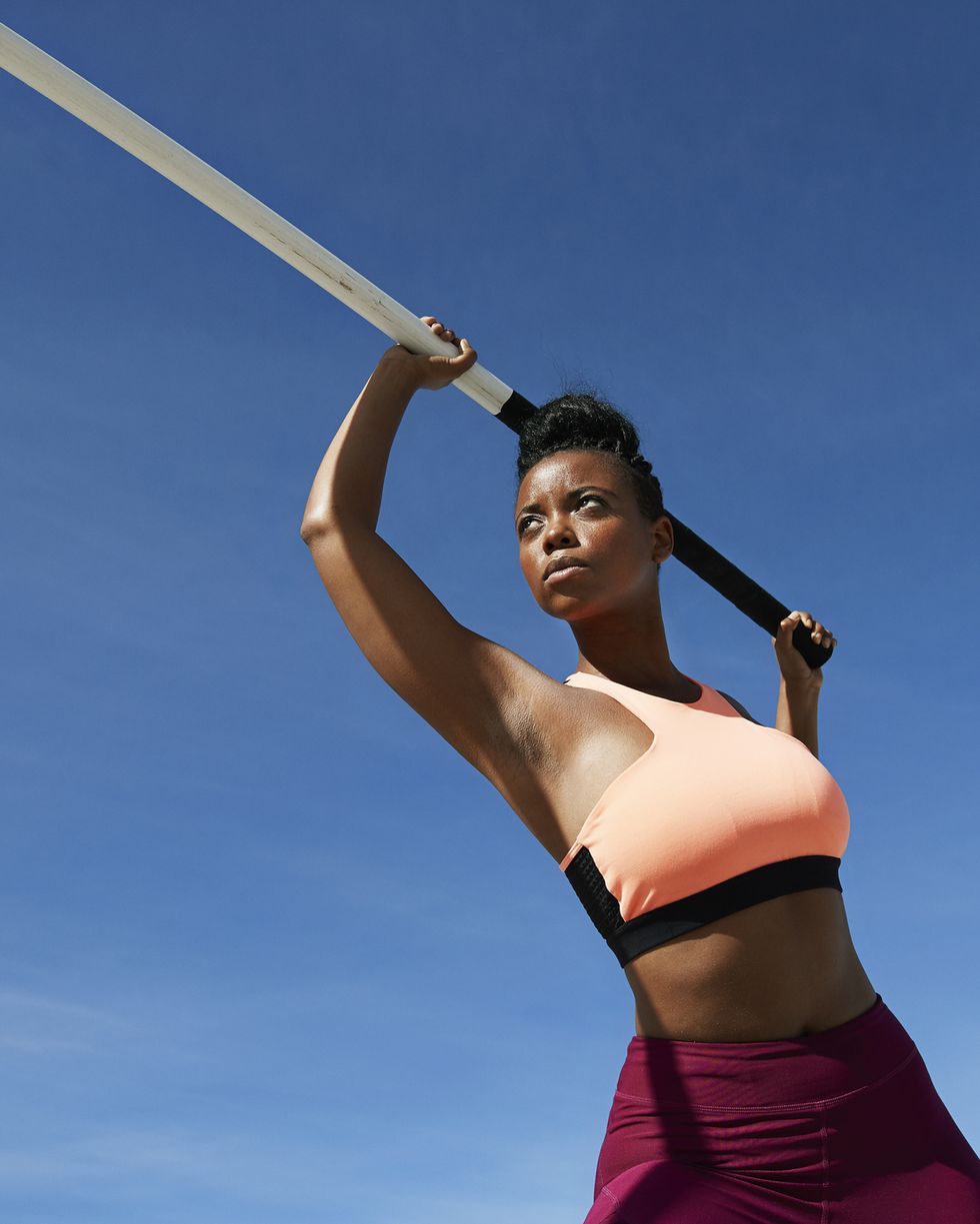 female athlete holding pole vault against blue sky