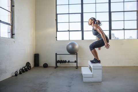 female athlete jumping on wooden seat in gym