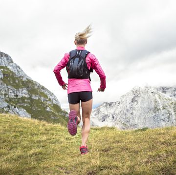 female athlete running up grassy mountain slope
