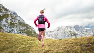 female athlete running up grassy mountain slope