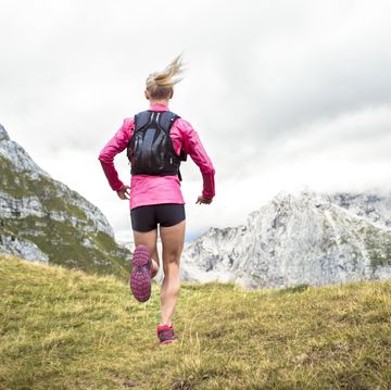 female athlete running up grassy mountain slope