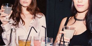 two stylish young women surrounded by alcoholic drinks