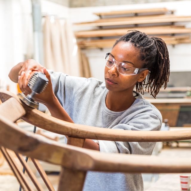 female black worker restoring an old chair in a woodworking studio