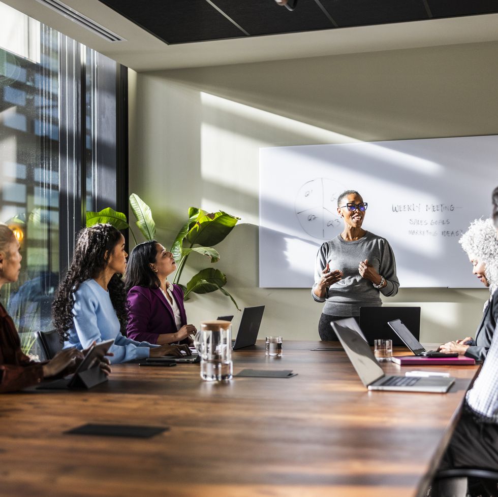 female business owner speaking to office workers in modern conference room