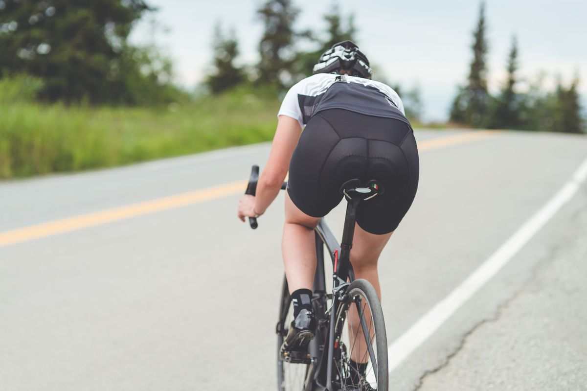 Female cyclist rides along a rural highway