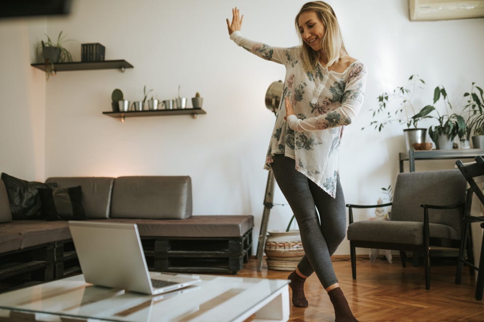 una mujer rubia hace un paso de baile en el salón de su casa