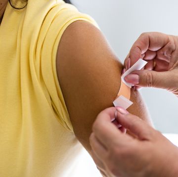 female doctor hands putting band aid on woman arm after giving vaccine