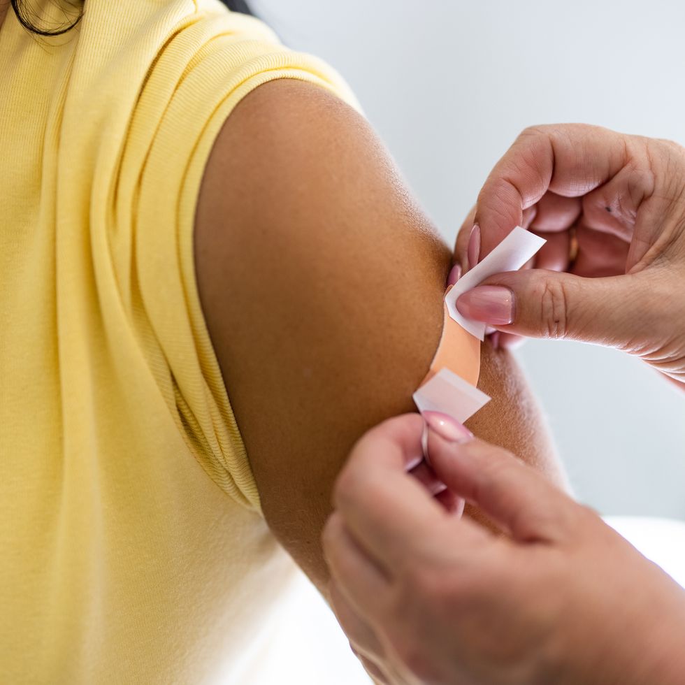 female doctor hands putting band aid on woman arm after giving vaccine