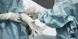 Female doctor helping surgeon wearing glove