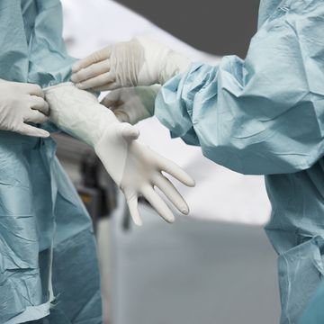 female doctor helping surgeon wearing glove