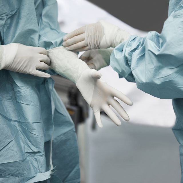 female doctor helping surgeon wearing glove
