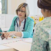 Female doctor reviewing medical records with nurse at desk