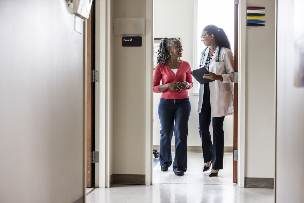 female doctor talking with senior woman in doctor's office hallway