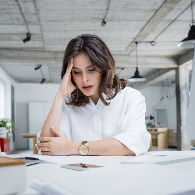 female entrepreneur with headache sitting at desk