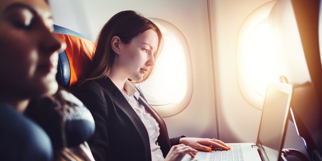 Female entrepreneur working on laptop sitting near window in an airplane