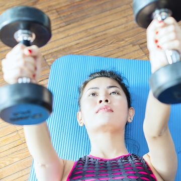 female fitness instructor working out, doing bench press with dumbbells in health club