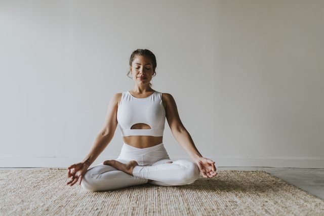female fitness teacher meditating in lotus position at yoga studio