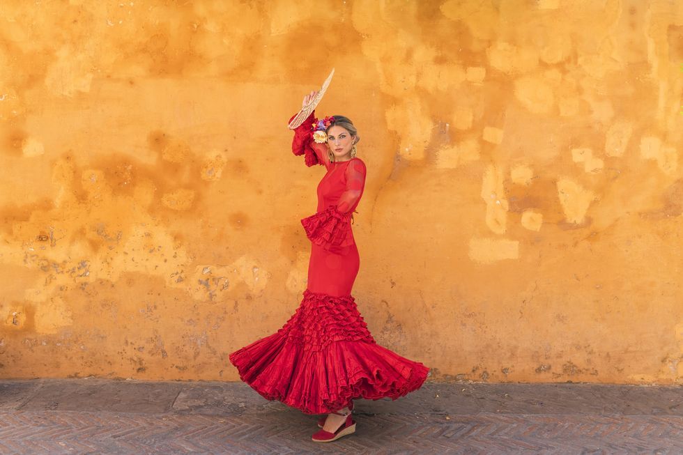 female flamenco artist with hand fan dancing on footpath