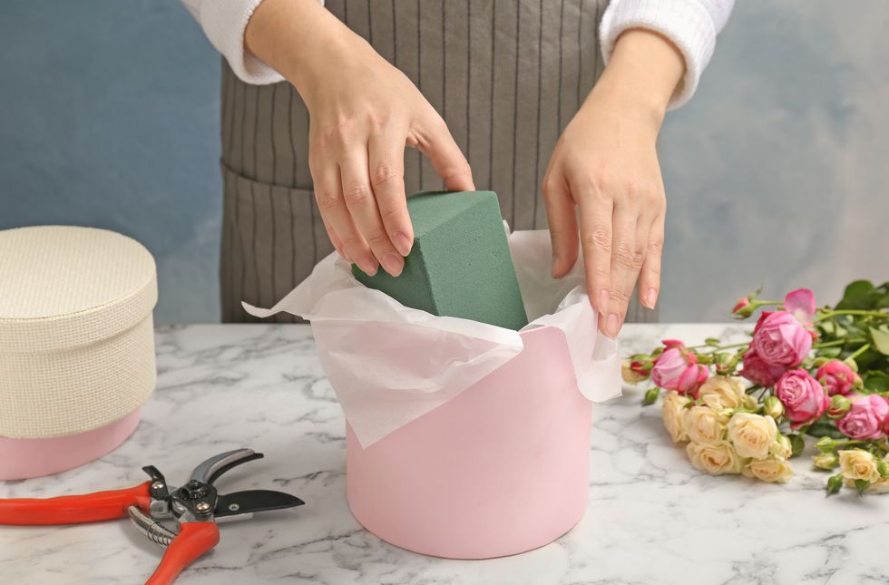 Female florist using floral foam for work at table