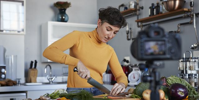 Female food vlogger making video while prepping vegetables in kitchen