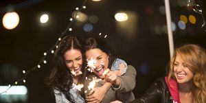 Female friends with sparklers at rooftop party