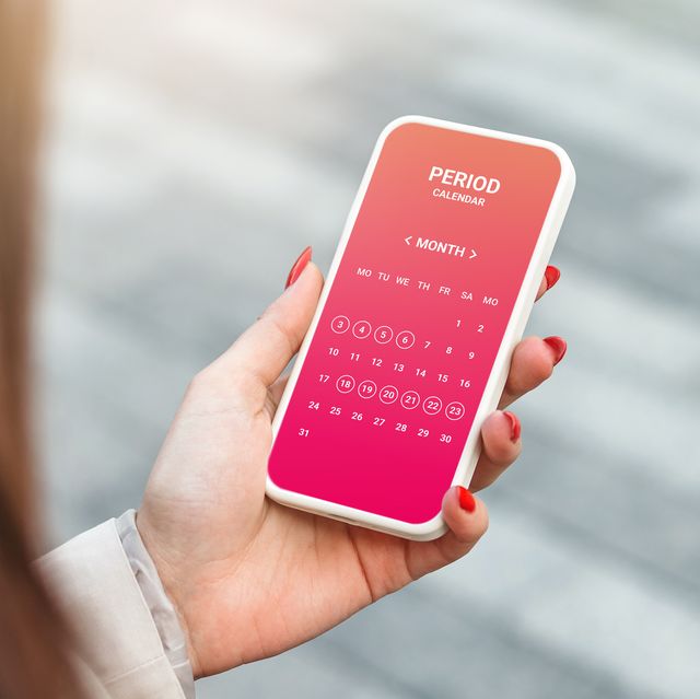 female hand holding a mobile phone with an open menstrual cycle calendar application
